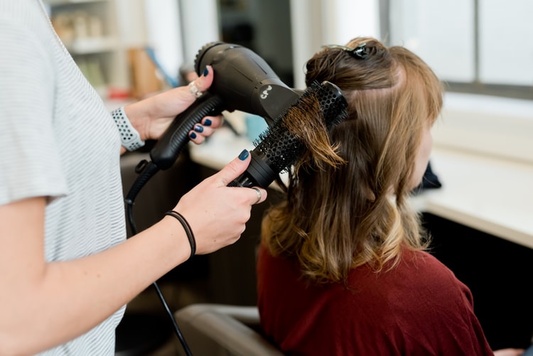 mulher escovando e secando cabelo de outra mulher